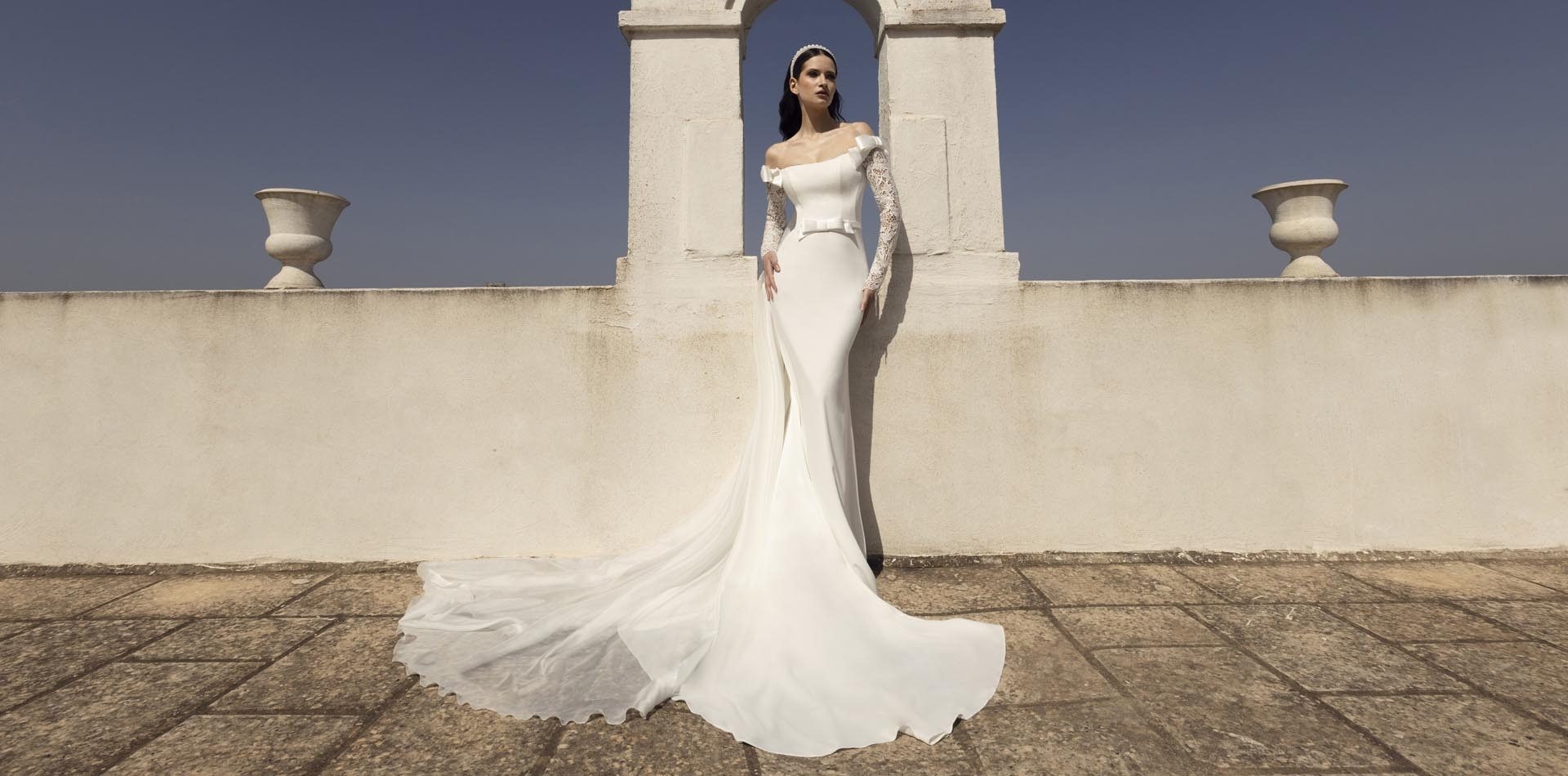 Sposa in abito a sirena Pietro De Mita con maniche in pizzo sulla terrazza di una masseria, contro il cielo
