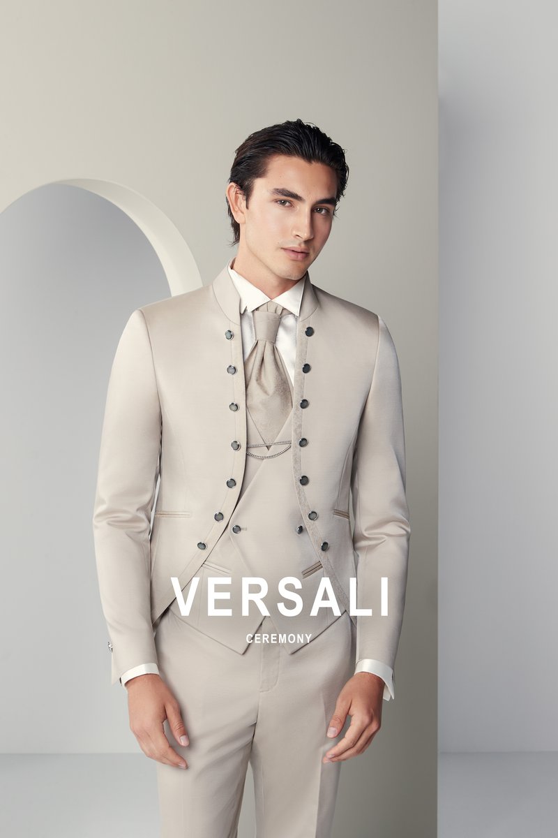 Sposo in abito tre pezzi beige Andrea Versali con giacca a collo coreano e doppia fila di bottoni, gilet e plastron