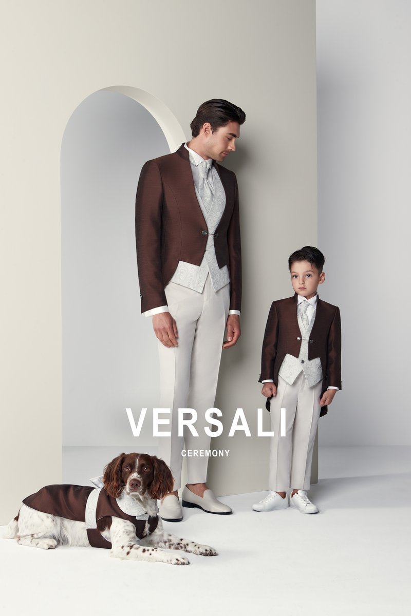 Padre e figlio in tight marrone e pantalone avorio Andrea Versali, con un cane in mantellina coordinata