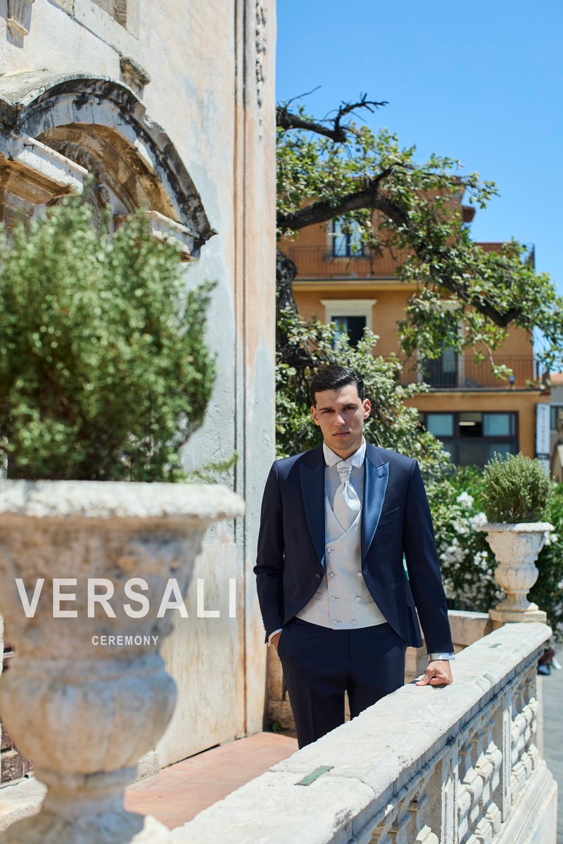 Sposo in abito blu notte Andrea Versali con gilet e plastron grigio perla, su una terrazza con balaustra in pietra